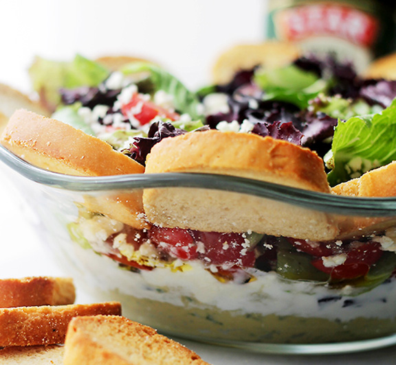 A fantastic recipe filled with garlic hummus, yogurt, artichokes, olives, feta cheese and more. The perfect salad dip for parties, picnics and family get-togethers.
 #STARFineFoods