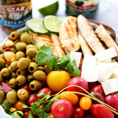 A huge bowl of flavor-packed, colorful chicken salad with tomatoes, Fiesta Blend olives and Mexican cheese. This Lime Cumin Chicken Salad will hit the spot! #STARFineFoods